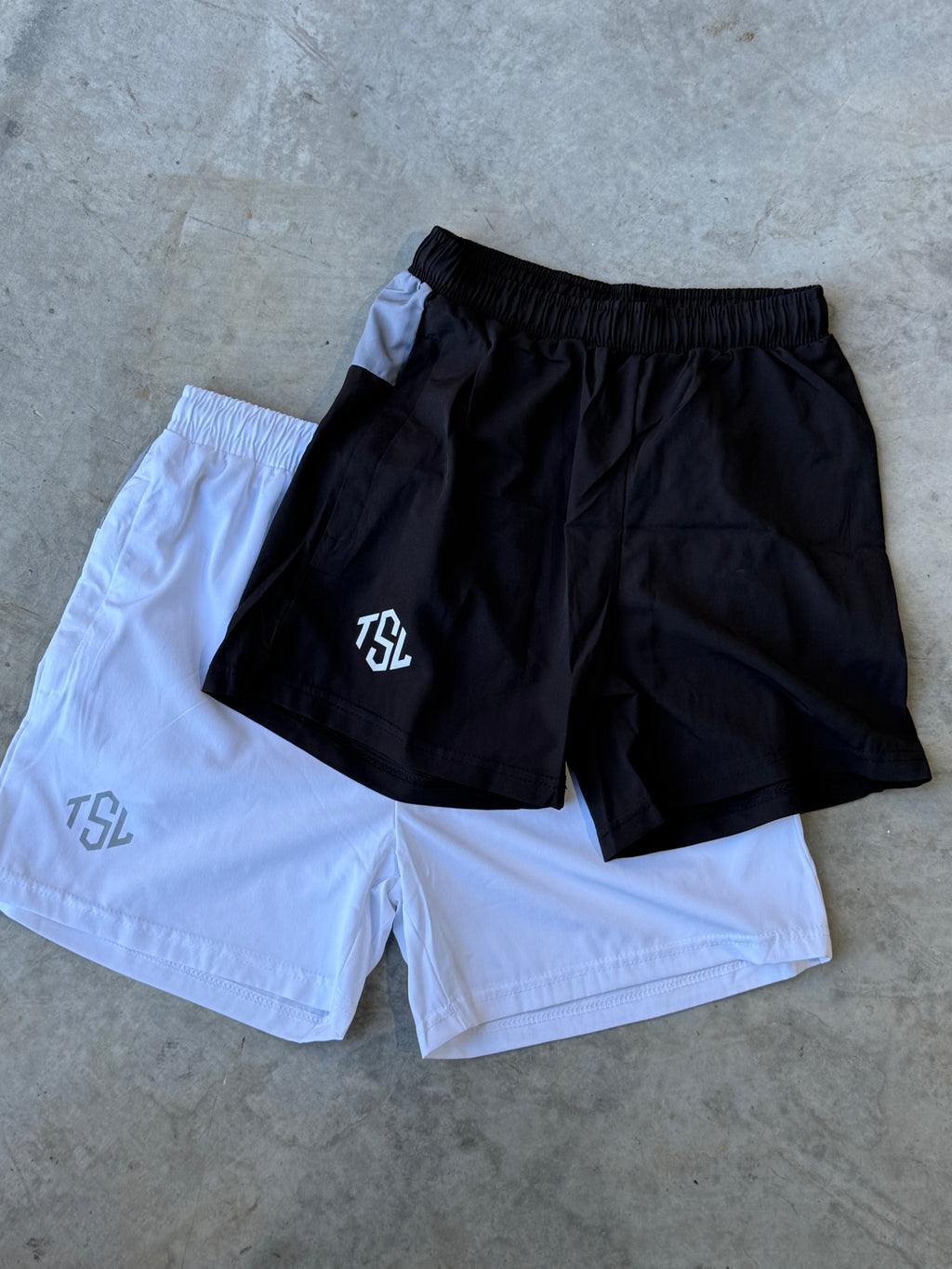 Black and White set of TSL Performance Shorts flat lay front side, stacked – lightweight four-way stretch gym shorts from Australian activewear brand